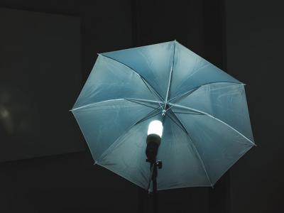 A photography umbrella lit by a single light.