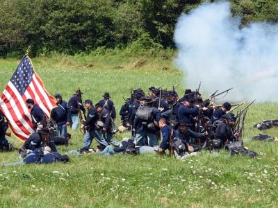 Actors as soldiers in a civil war reenactment with an American flag on the left.