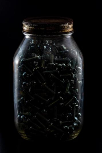 Jar of screws backlit.