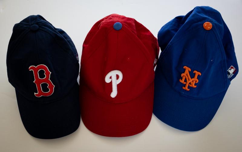 Three t-ball caps in a row, black, red, and blue.
