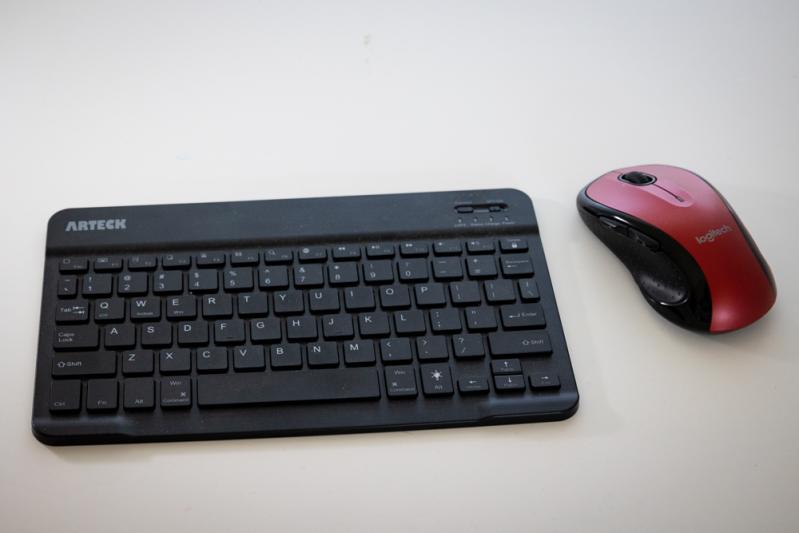 Keyboard and red mouse on white surface.