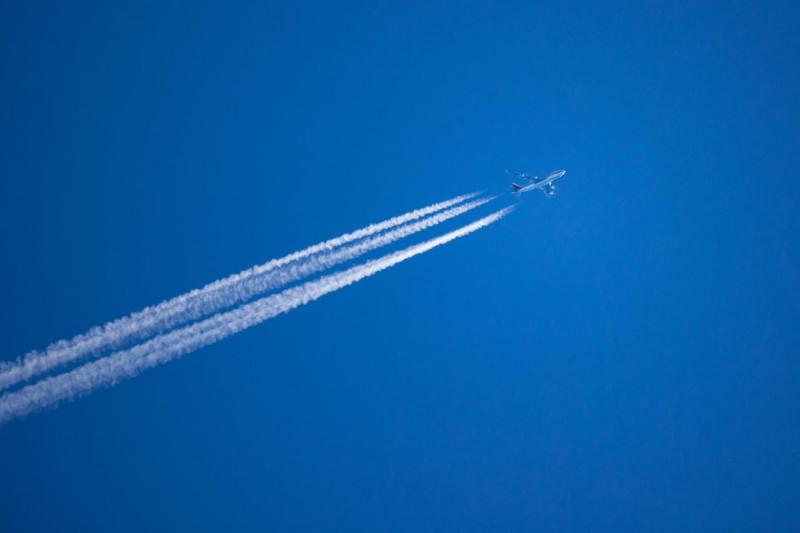 Jet in blue sky with contrail.