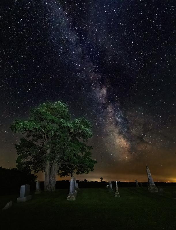 Maker: Brian Narveson Entered in: 2022 January Competition - A Open Score: 38 points  1st PlaceJudge's comments: Much detail in the Milky Way; no noise; the light in the foreground is very cool and does not quite match the night skyMaker's comments: This image was shot at the cemetery south of La Crosse.  It was shot with my 7D Mark ii and a Canon 10mm lens set at f/3.5.   Camera set in Manual and tripod mounted.  ISO-4000, 20 second exposure.  Noise reduction done in Topaz Noise AI.  Other processing done in Lightroom.
