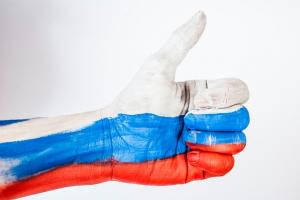 Side view of arm and hand with the thumb up and skin painted white, blue, and red.
