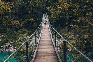Looking down a wooden bridge over a river in a forest.