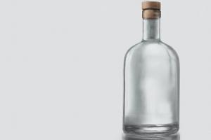 Empty bottle with cork on the right of a grey background.