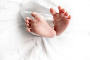 Baby feet showing out of white sheet.