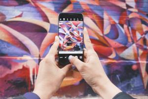 Hands holding a cellphone while photographing a colorful wall.